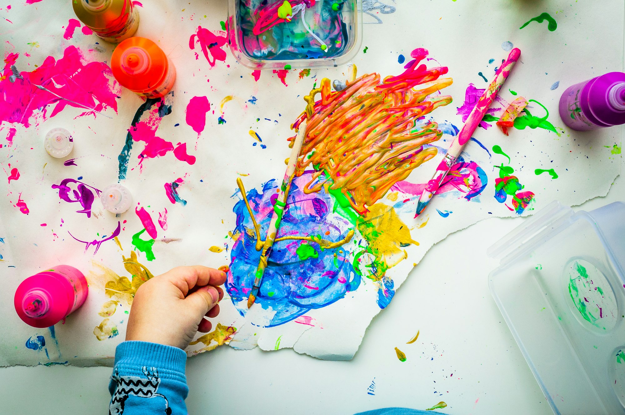 Niño pintando con témperas de colores sobre una hoja blanca